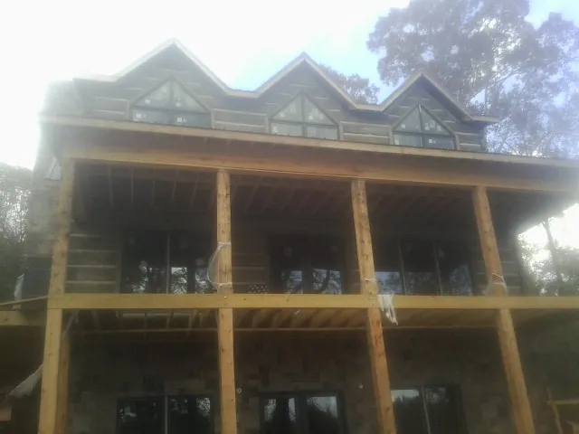 Dormers and porch framing on a large log home under construction — Roof Coating work by our crew in Miami Beach