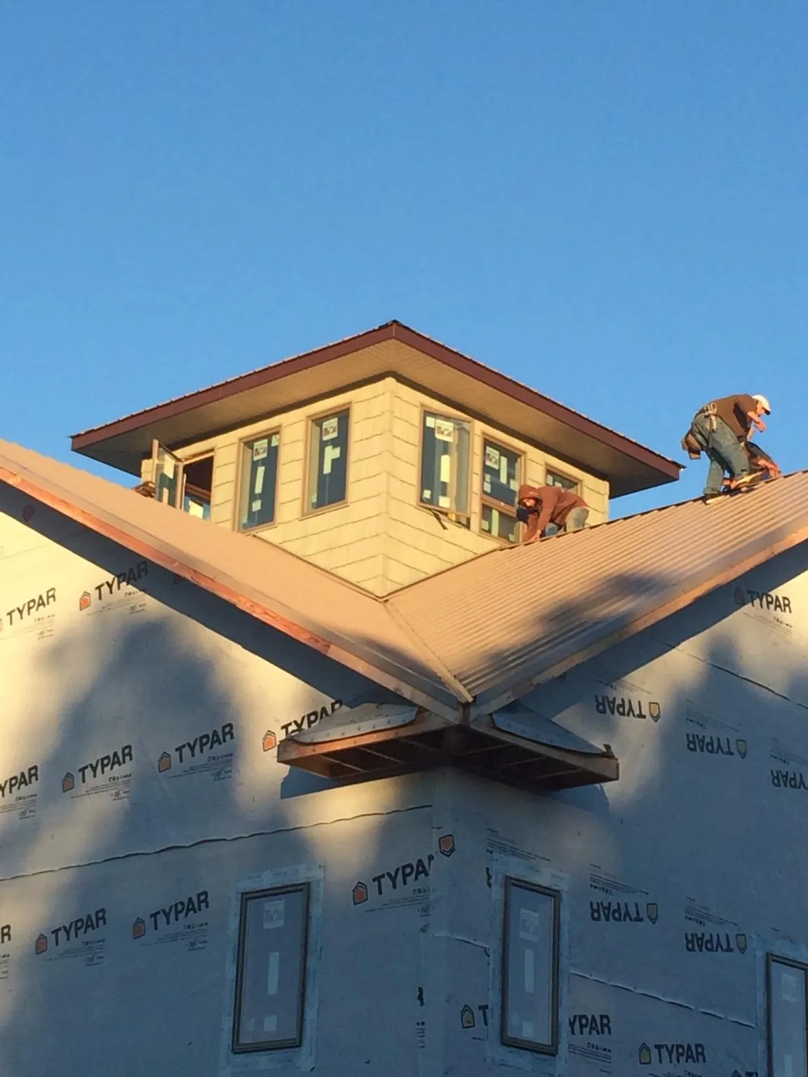 Roofers working around a rooftop cupola on a new metal roof at sunset — Roof Waterproofing in Miami Beach by Roofing Brothers